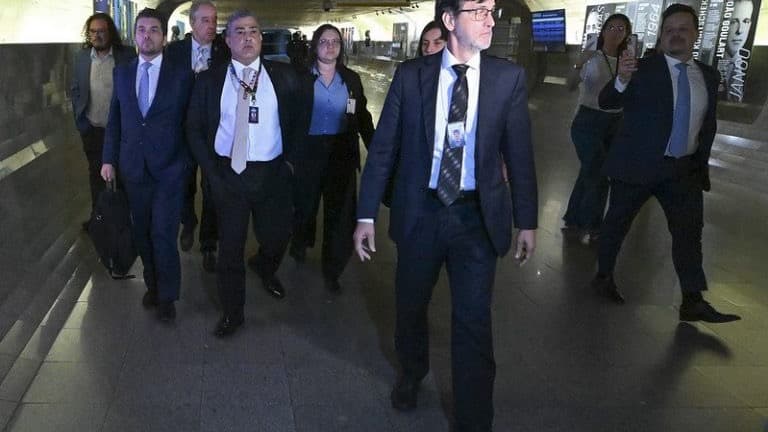 Carlos Roberto Ferreira Lopes, de terno escuro e crachá de identificação, é conduzido por corredor do Congresso Nacional acompanhado de assessores