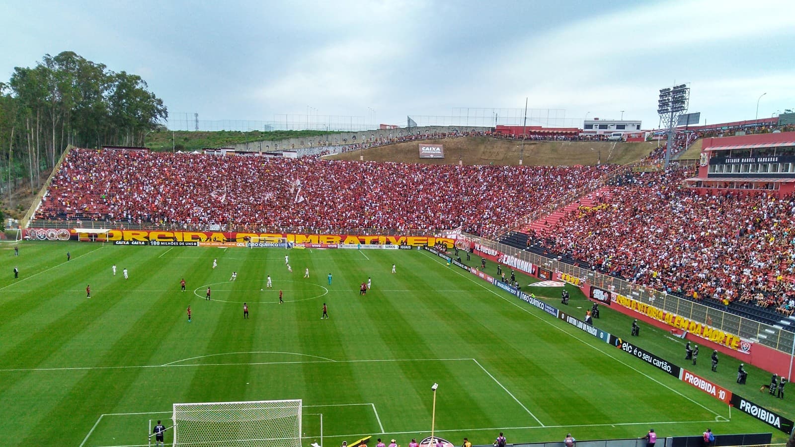Estádio Barradão lotado durante partida do Vitória, com torcida nas arquibancadas e jogadores em campo