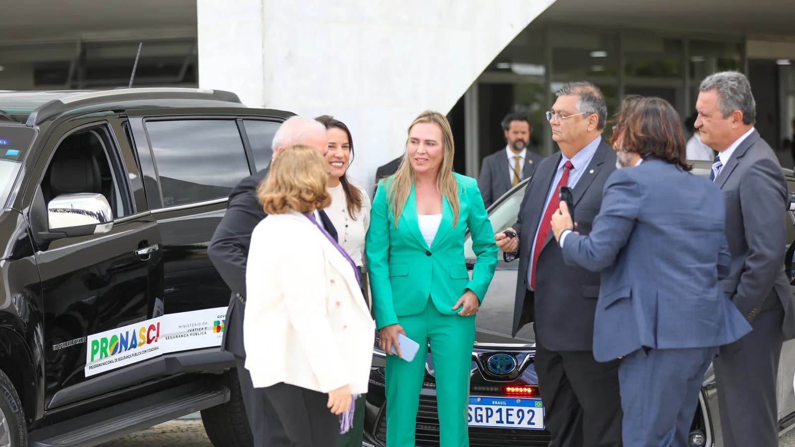 A governadora do DF, Celina Leão, de terno verde, conversa com autoridades ao lado de uma viatura
