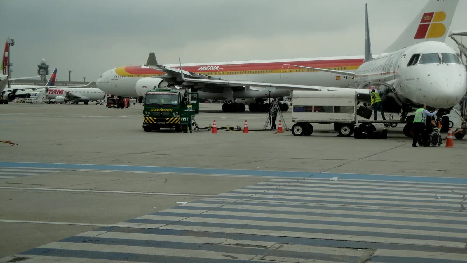 Pátio de aeronaves no Terminal 4 do Aeroporto de Guarulhos, com equipe de solo trabalhando ao lado de um avião