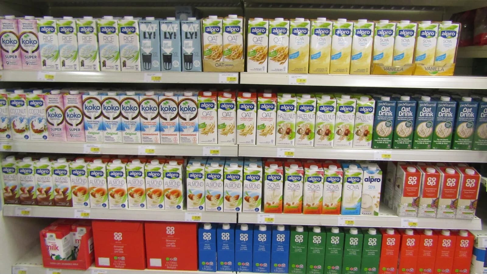 Prateleira de supermercado com diferentes marcas e tipos de leite