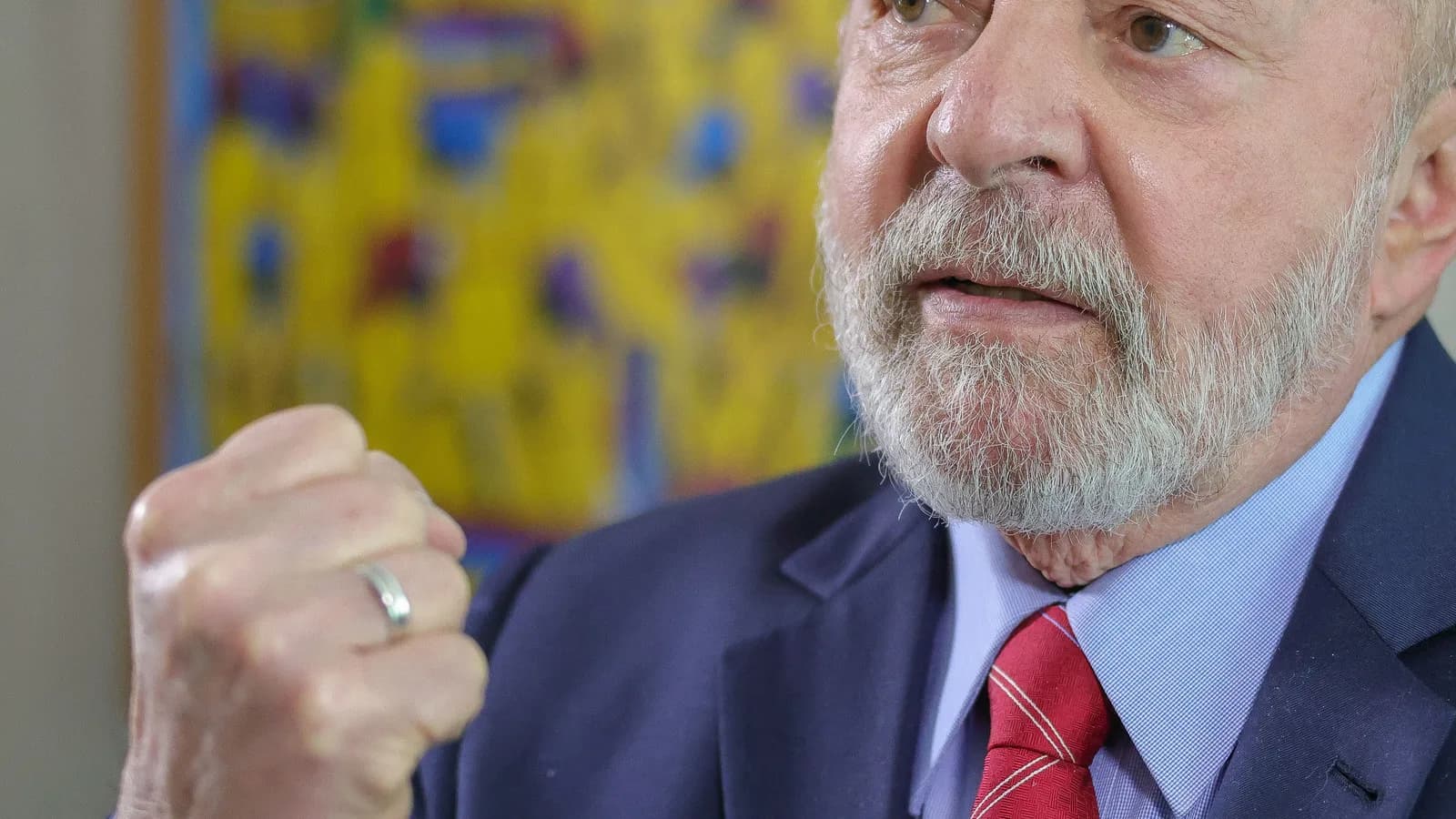 Lula gesticula durante entrevista, com bandeira do Brasil ao fundo