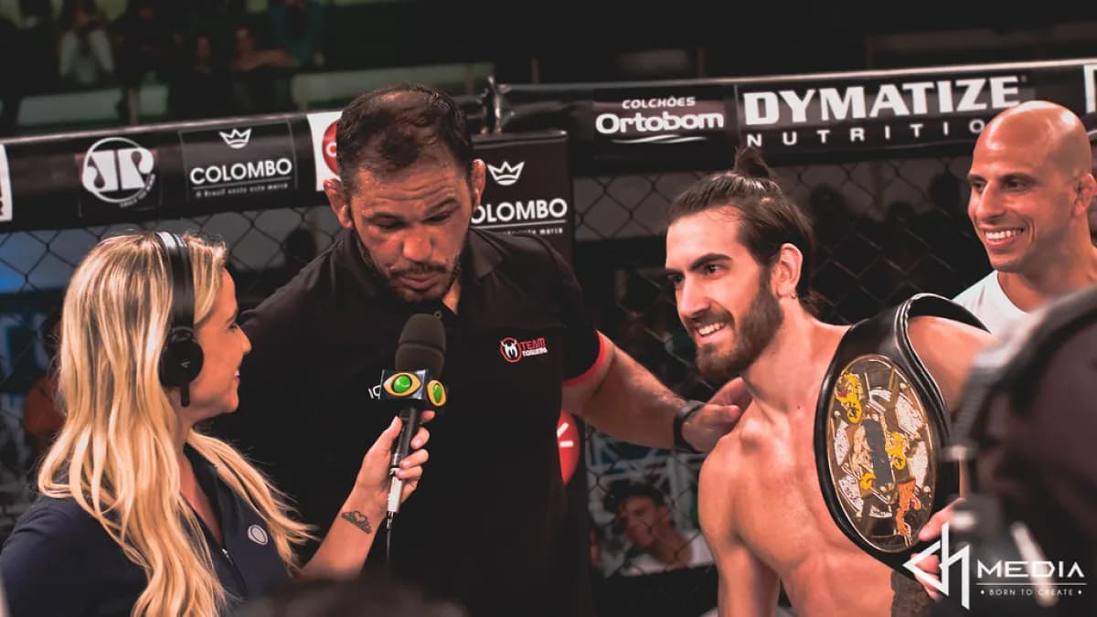 Lutador de MMA é entrevistado no octógono ao lado do cinturão de campeão, em evento do Jungle Fight (foto de arquivo, outra edição)