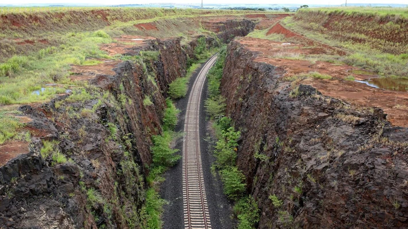 Trilhos de ferrovia cortando terreno no Brasil