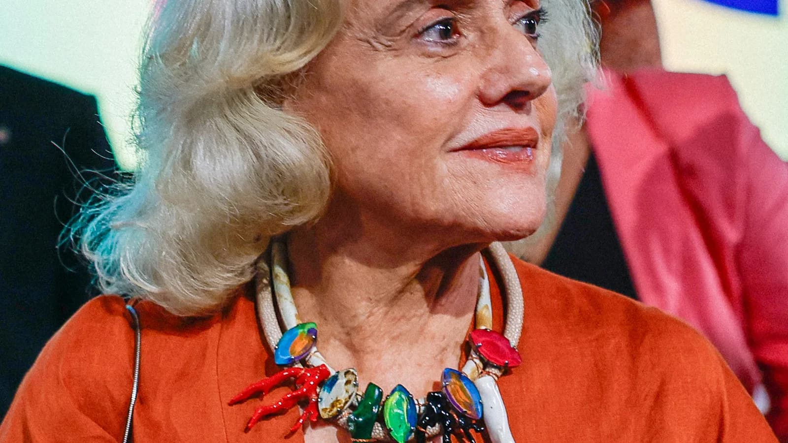Marieta Severo em evento público, com colar colorido e blazer laranja