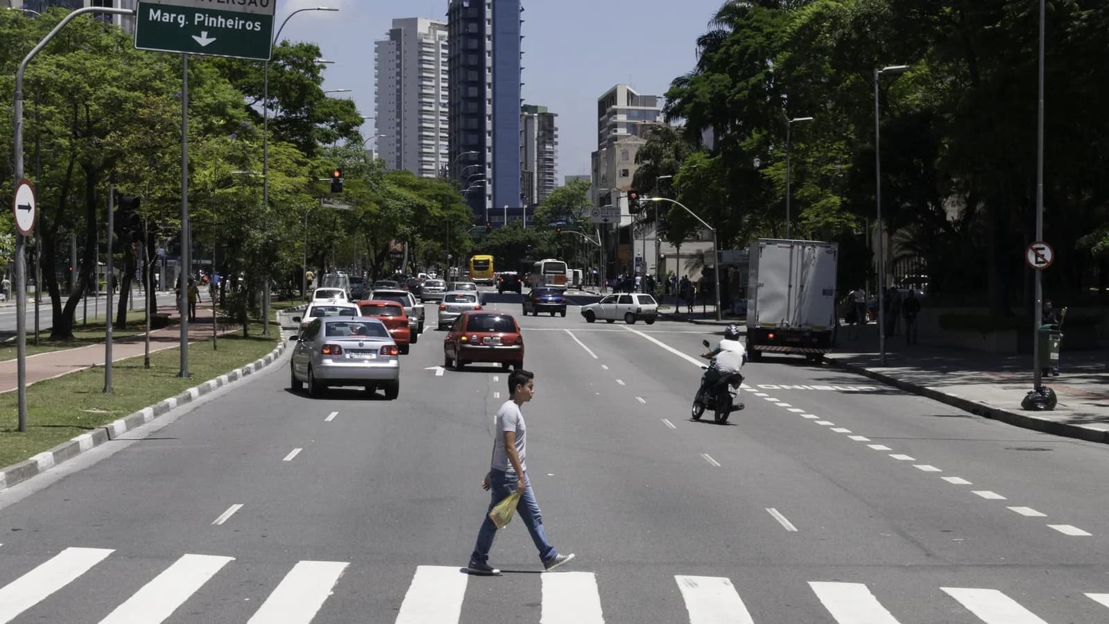 Avenida Faria Lima, no centro financeiro de São Paulo, com pedestre atravessando a rua e prédios comerciais ao fundo