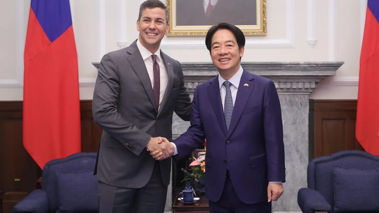 Presidente do Paraguai, Santiago Peña, aperta a mão do presidente de Taiwan, William Lai, diante das bandeiras dos dois países