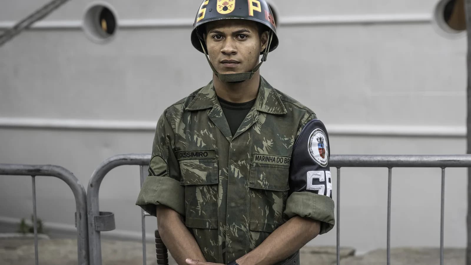 Policial militar fardado em frente a grade de contenção