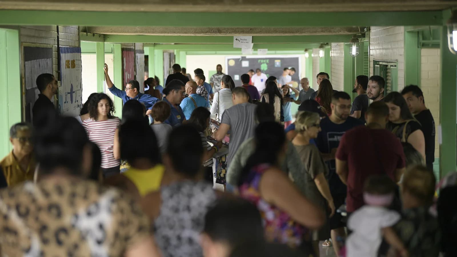 Eleitores em fila em seção eleitoral durante votação