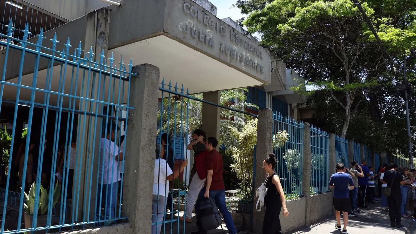 Pessoas entram por portão de escola usada como local de prova (foto de contexto)