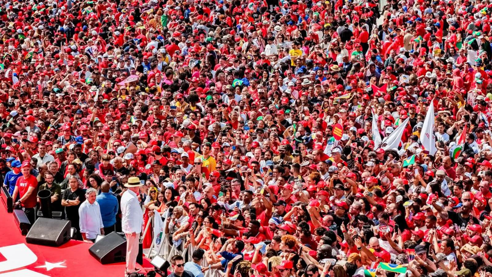 Multidão de apoiadores com bandeiras do Brasil em ato de campanha de Lula
