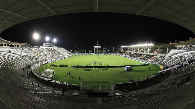 Vista interna do estádio de São Januário durante partida noturna, com torcida nas arquibancadas