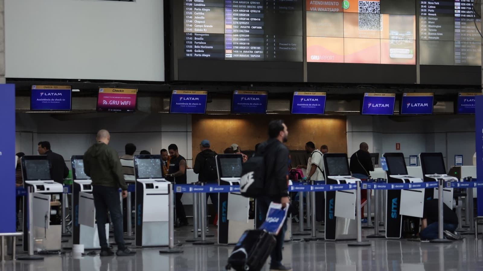 Imagem de arquivo do saguão de check-in do Aeroporto de Guarulhos, com passageiros diante dos totens de autoatendimento e do painel de voos