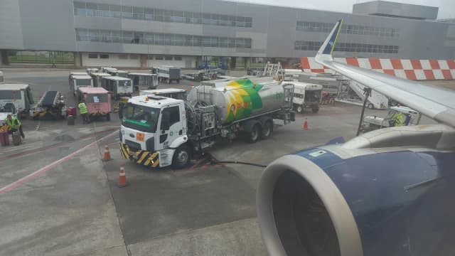Caminhão abastece avião com querosene de aviação em pátio de aeroporto