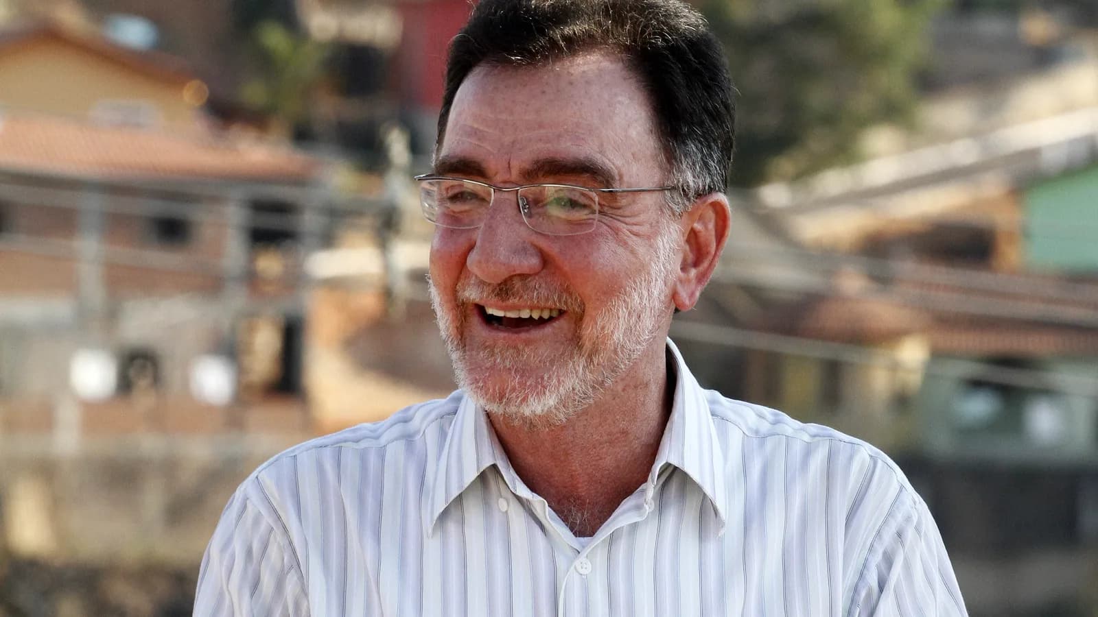 Patrus Ananias sorri em foto ao ar livre com Minas Gerais ao fundo