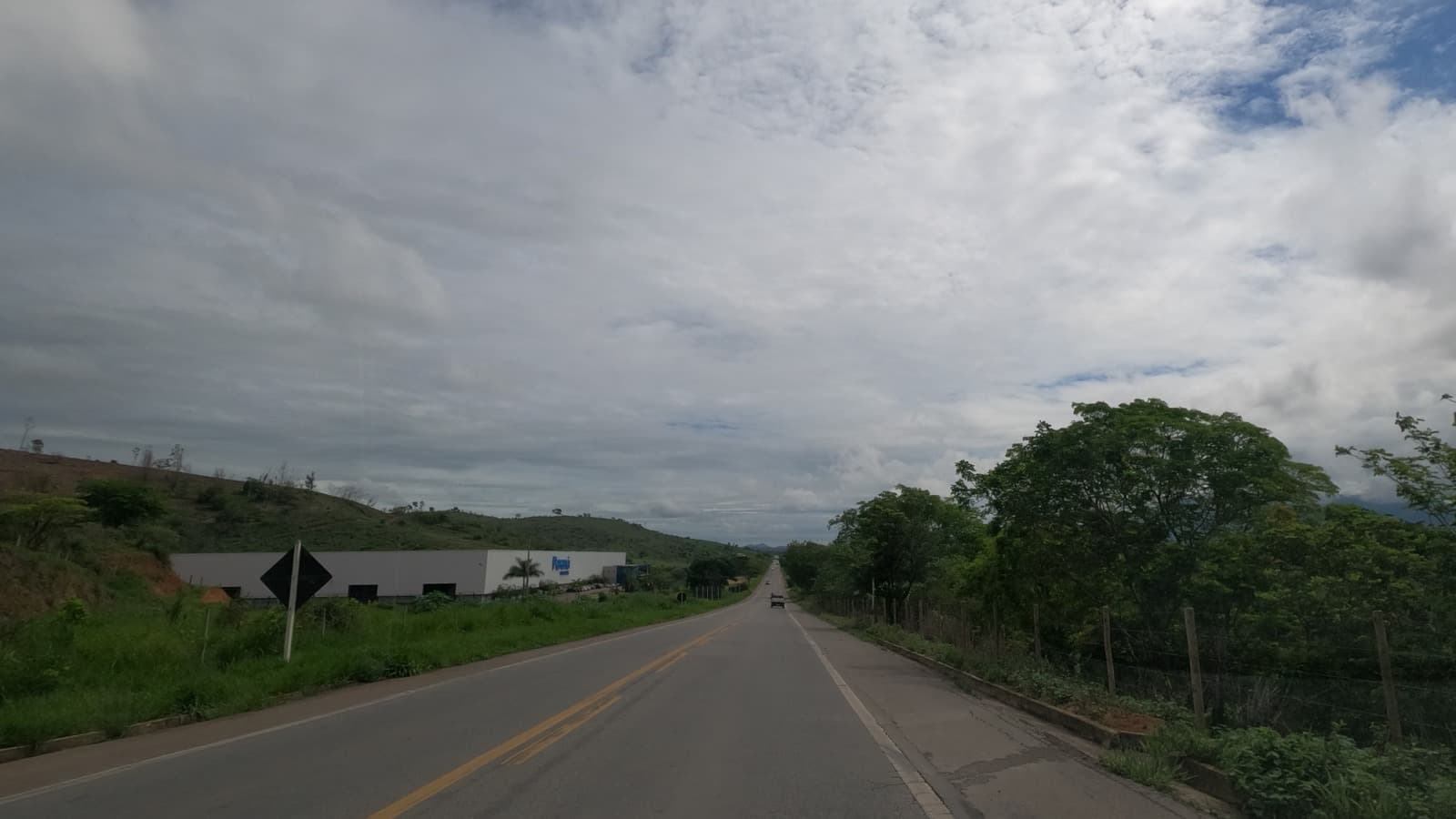 Trecho da rodovia BR-381 em Governador Valadares (MG), com vegetação nas margens e um veículo trafegando ao longe