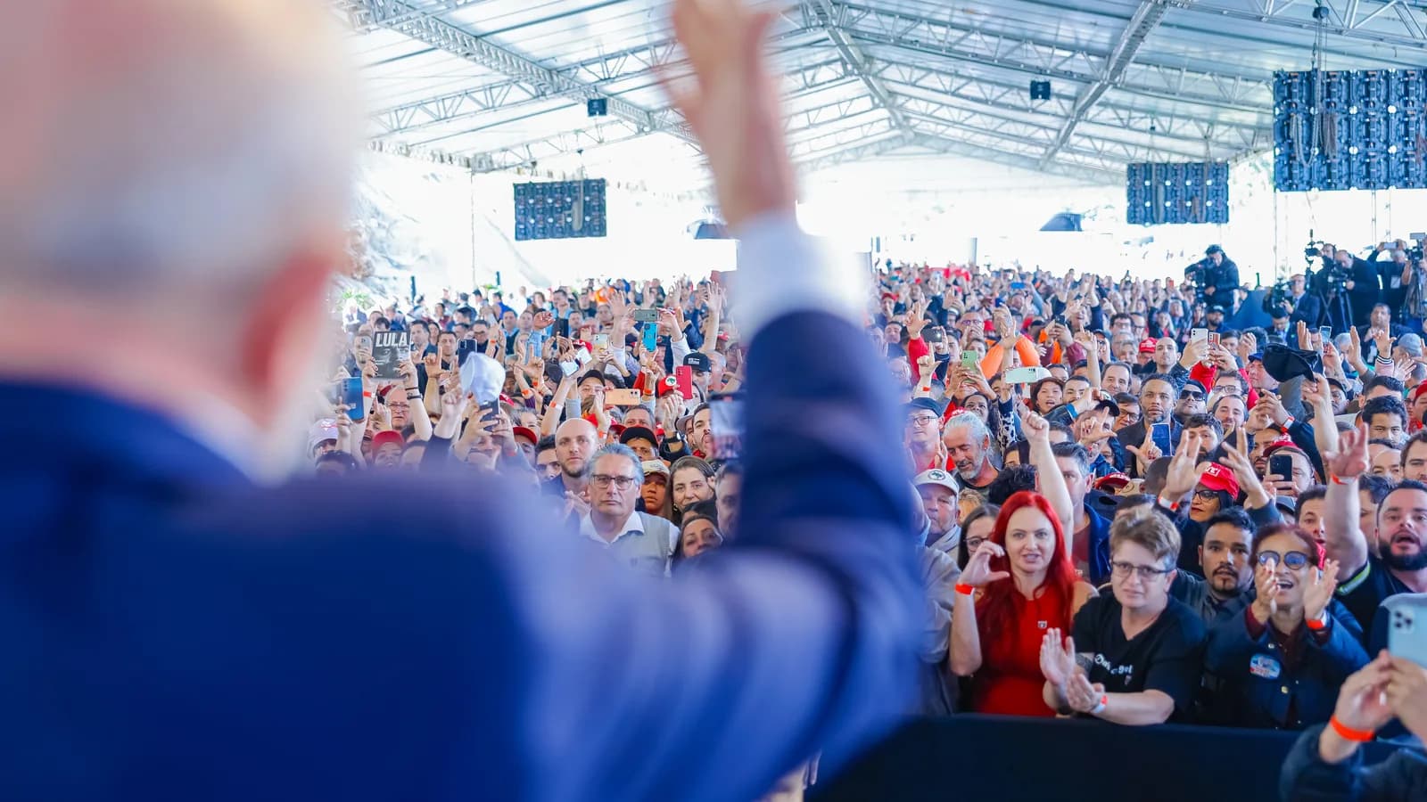 Lula, de costas, acena com o braço erguido para multidão em evento em Florianópolis (foto de arquivo, 2024)