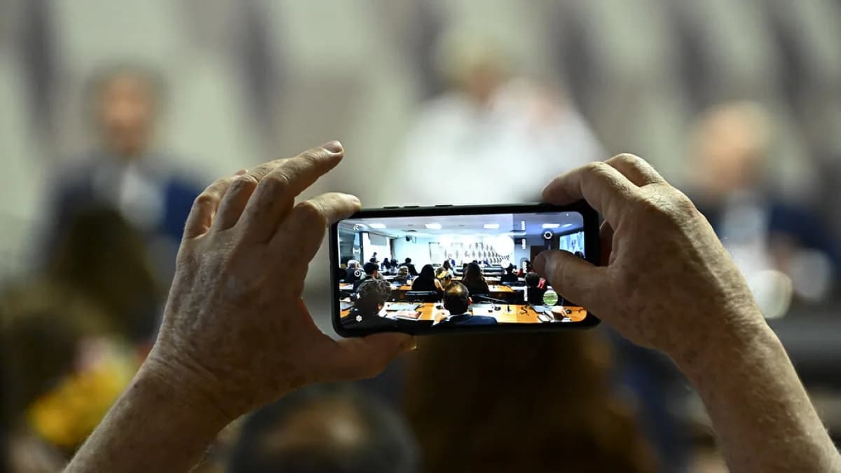 Mãos seguram um celular para fotografar documento, foto de arquivo ilustrativa