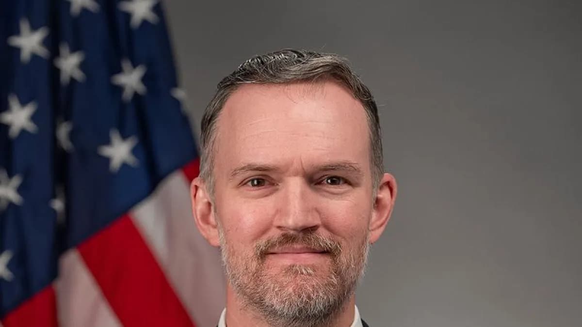 Retrato oficial de Jamieson Greer, representante comercial dos Estados Unidos, com a bandeira americana ao fundo