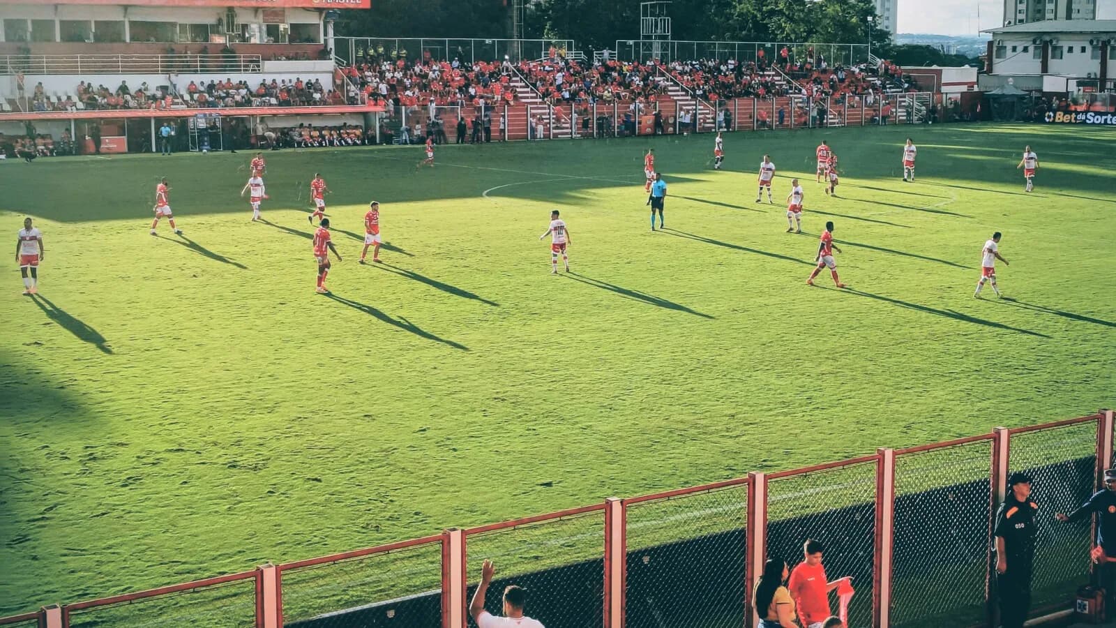 Jogadores do Vila Nova em campo no Estádio Onésio Brasileiro Alvarenga, com a torcida ao fundo