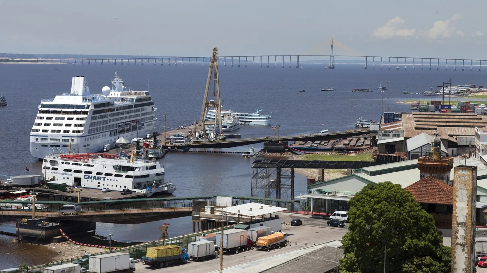 Vista aérea do porto de Manaus, com navios, caminhões e a ponte sobre o Rio Negro ao fundo