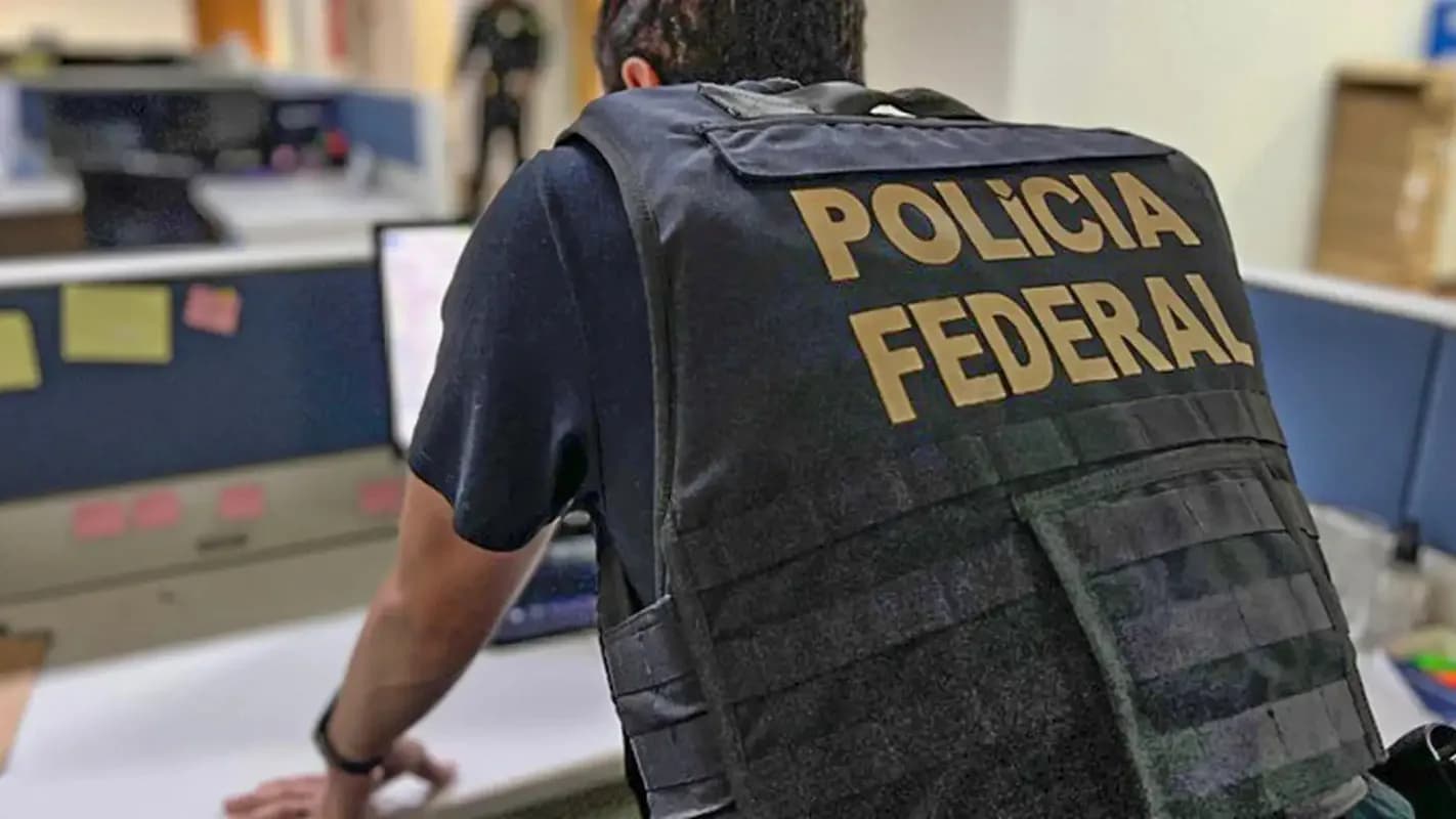 Agente da Polícia Federal de costas durante operação em escritório
