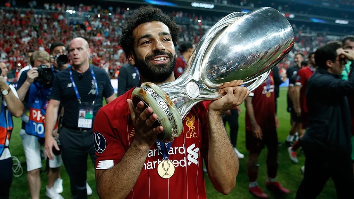 Mohamed Salah segura troféu em campo com camisa vermelha do Liverpool