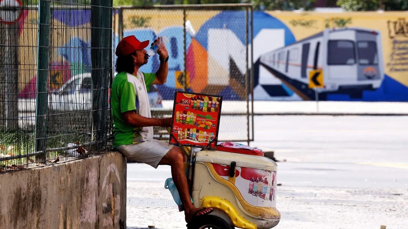 Trabalhador ambulante bebe água para se hidratar durante dia de calor forte na rua