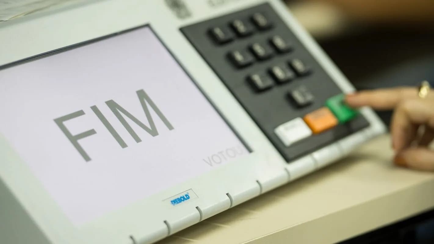 Mão de eleitor confirma o voto em urna eletrônica