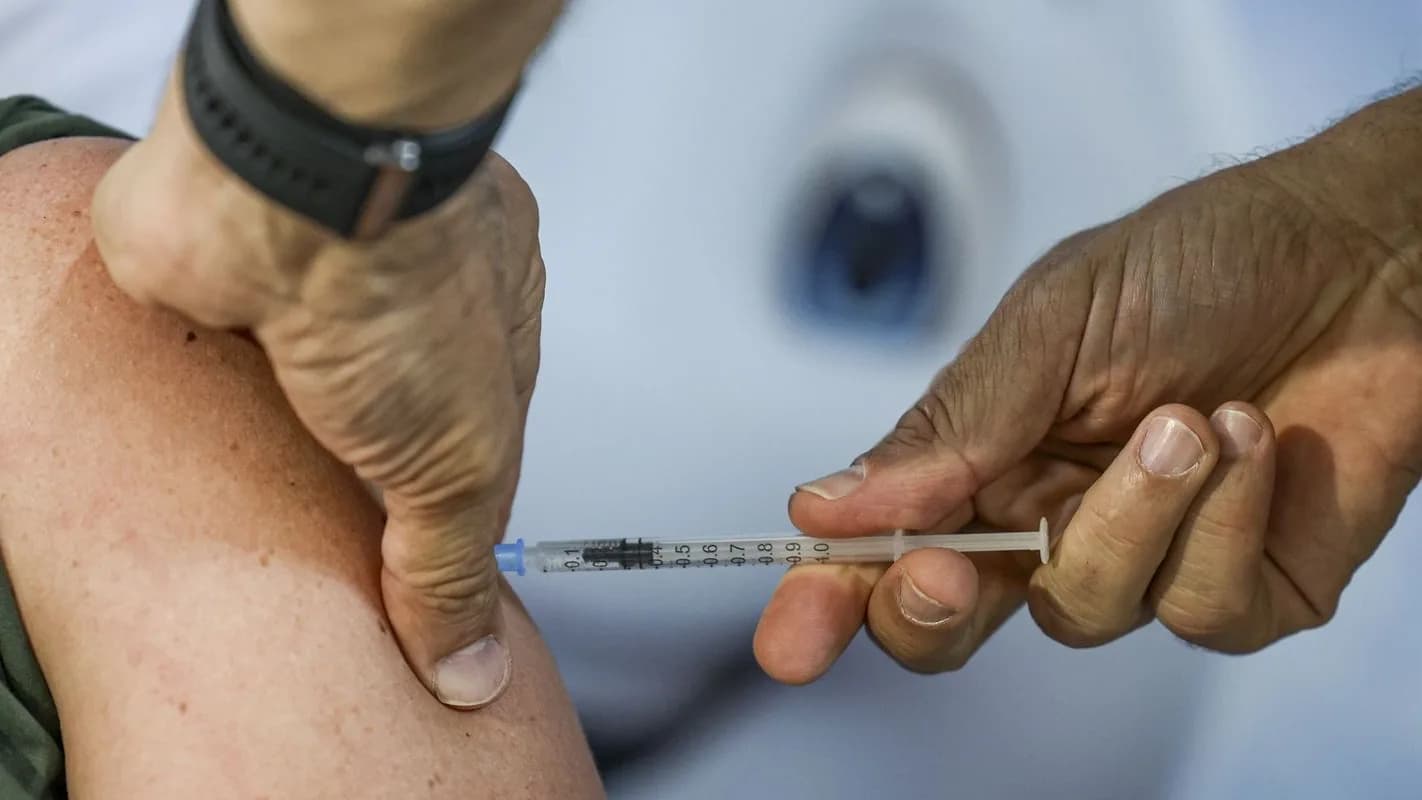 Profissional de saúde aplica dose de vacina no braço de um paciente