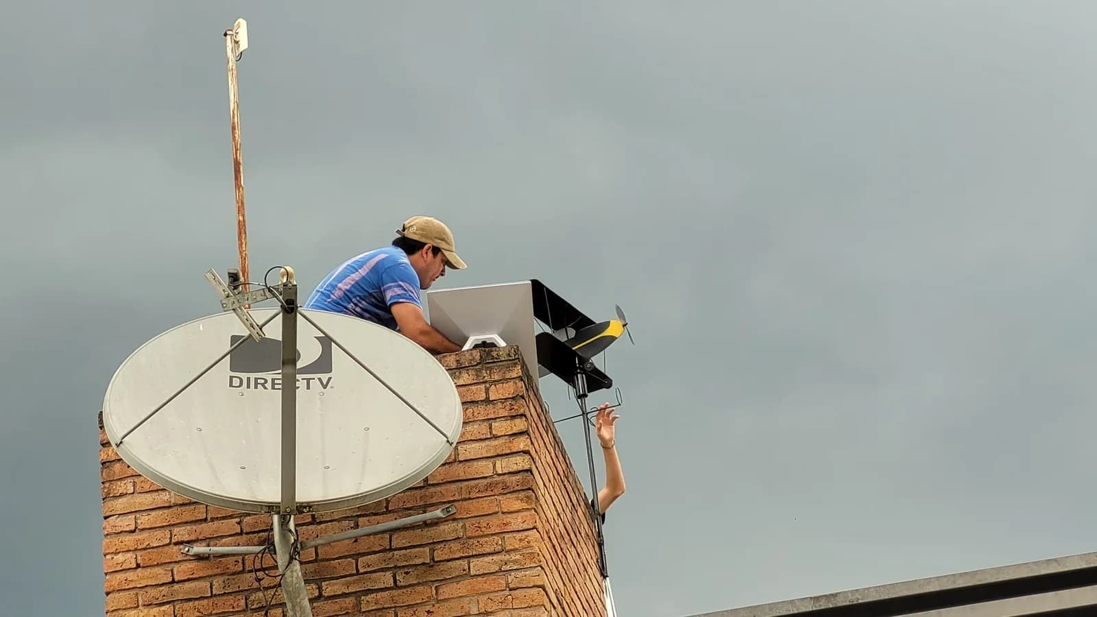 Homem instala antena e terminal de usuário do Starlink em telhado
