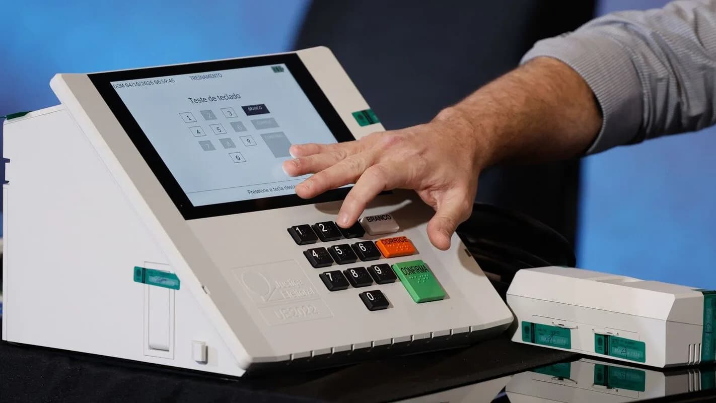 Mão de eleitor aperta tecla do teclado de uma urna eletrônica durante teste
