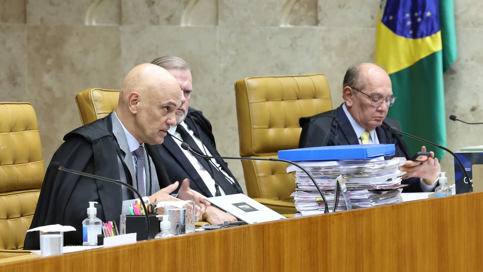 Ministros do Supremo Tribunal Federal, de toga, durante sessão plenária em Brasília, com pilha de processos sobre a bancada; imagem de arquivo de abril de 2026