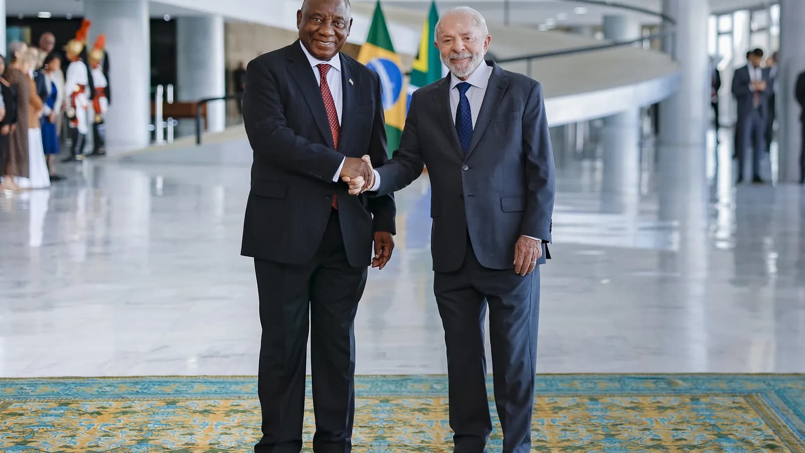 Lula sorri ao lado do presidente da África do Sul, Cyril Ramaphosa, em cumprimento no Palácio do Planalto