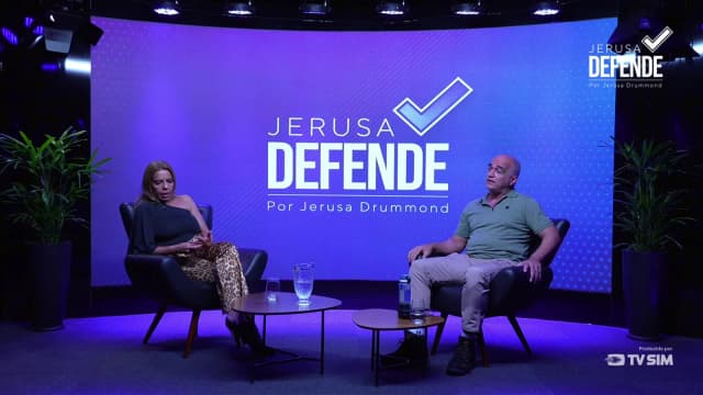 Jerusa Drummond entrevista Márlon de Carvalho Leão em plano aberto do estúdio do programa Jerusa Defende, enquanto ele relata a reconstituição da madrugada da morte da capitã Michelle Leão
