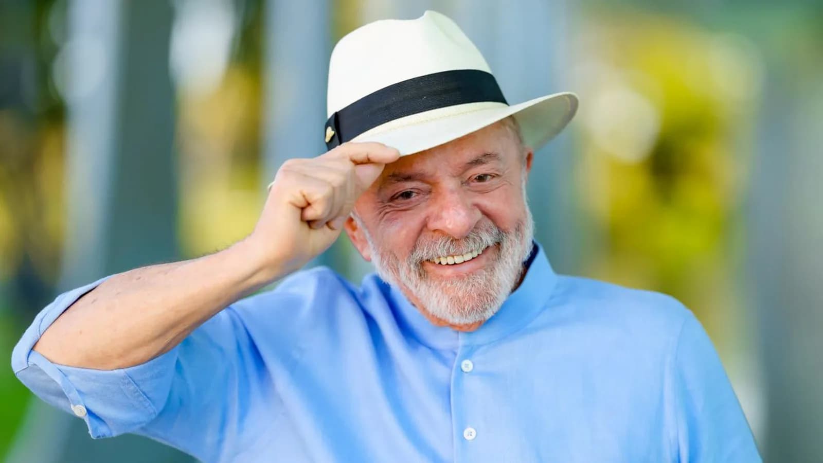 Lula sorridente, usando chapéu de palha, em evento ao ar livre