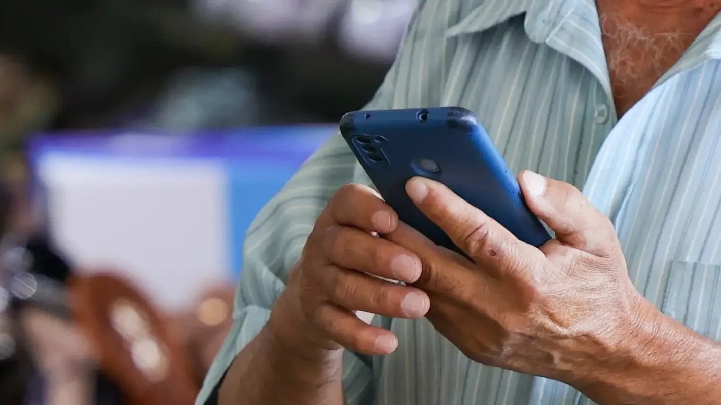 Homem segura celular nas mãos, em foco em close nos dedos e no aparelho