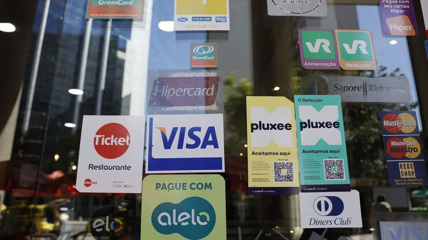 Vitrine de comércio com adesivos de várias bandeiras de vale-alimentação e vale-refeição, como Ticket, VR, Alelo e Pluxee