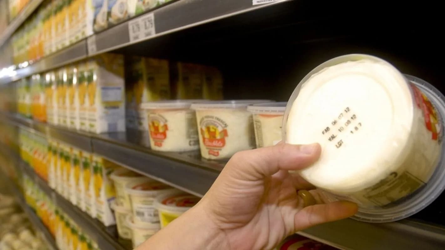 Consumidora observa rótulo de produto em prateleira de supermercado