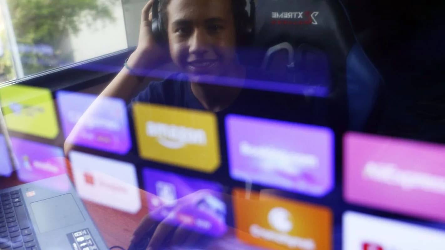 Pessoa assiste a conteúdo em tela com ícones de aplicativos de streaming e redes sociais