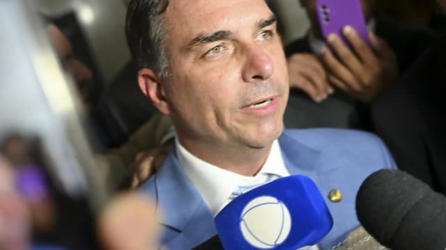 Senador Flávio Bolsonaro fala a jornalistas cercado de microfones e celulares