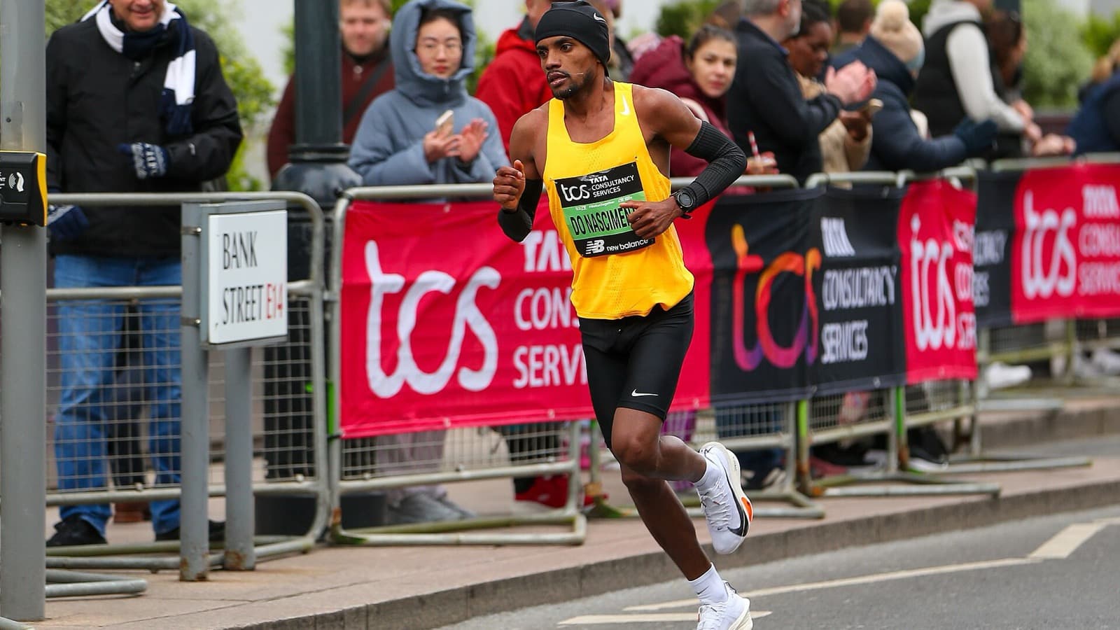 O maratonista Daniel do Nascimento corre com camiseta amarela na prova de elite da Maratona de Londres de 2024, com público atrás das grades; imagem de arquivo