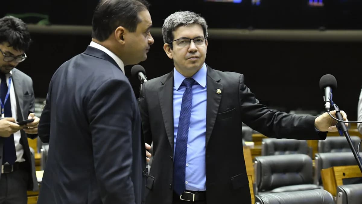 Dois deputados conversam em frente aos microfones no plenário do Congresso