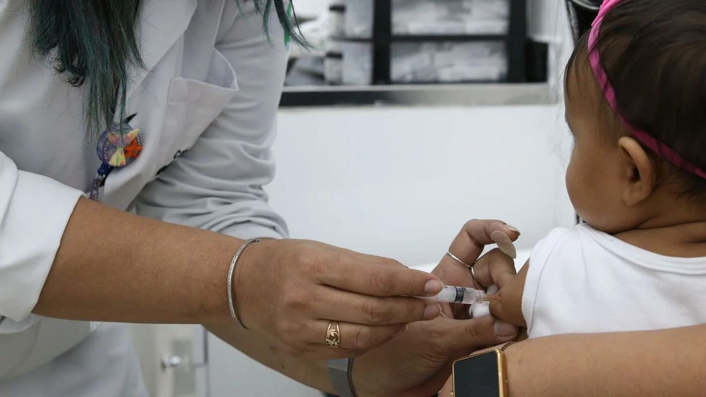 Profissional de saúde aplica vacina em bebê, ilustração sobre síndrome respiratória aguda grave