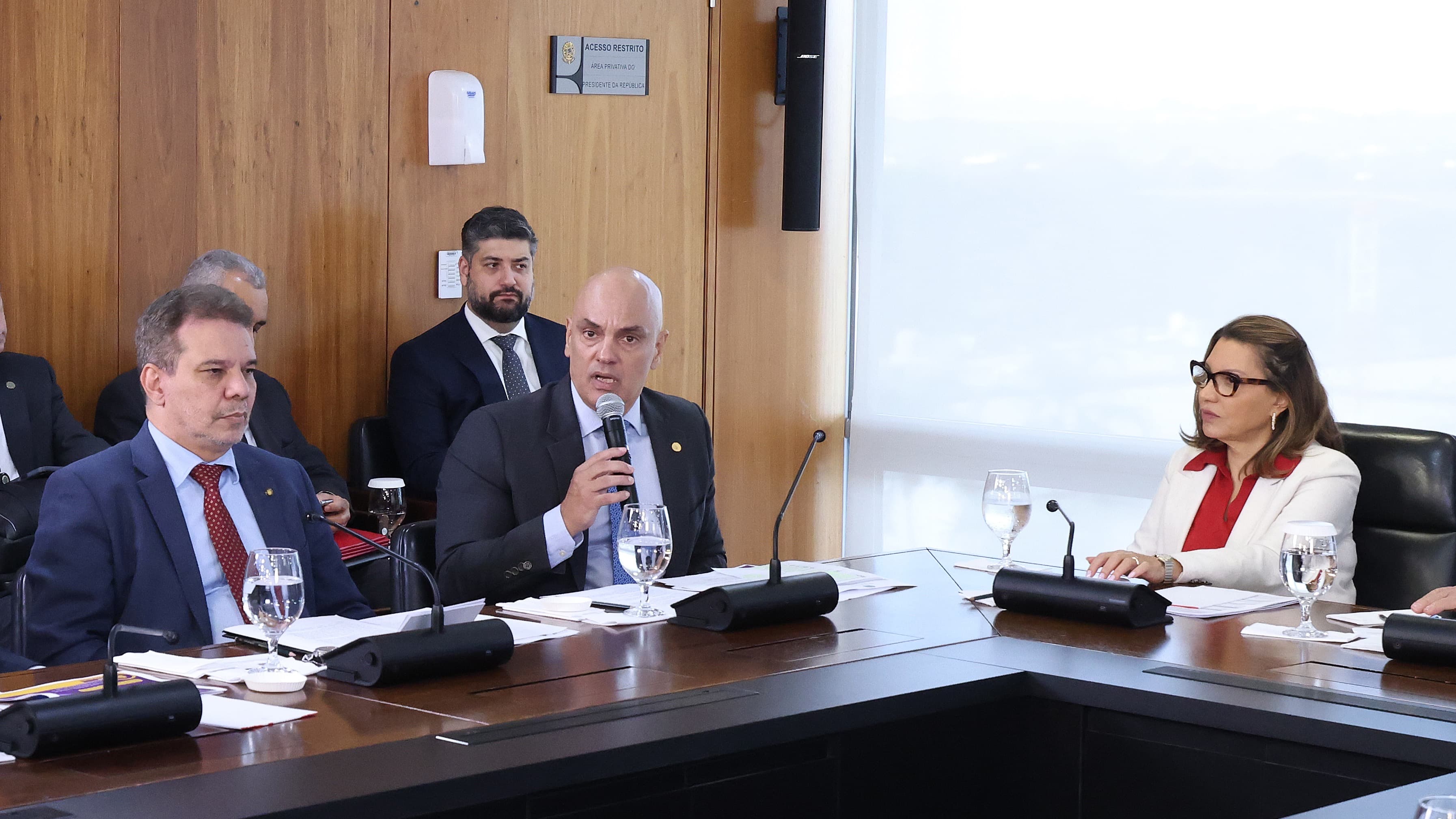 Ministro Alexandre de Moraes fala ao microfone durante reunião, ao lado de outras autoridades
