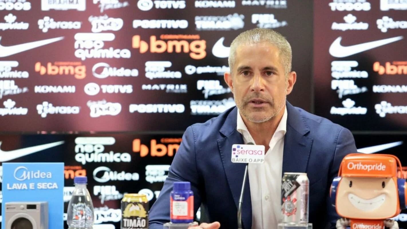 Sylvinho durante entrevista coletiva com camisa do Corinthians ao fundo