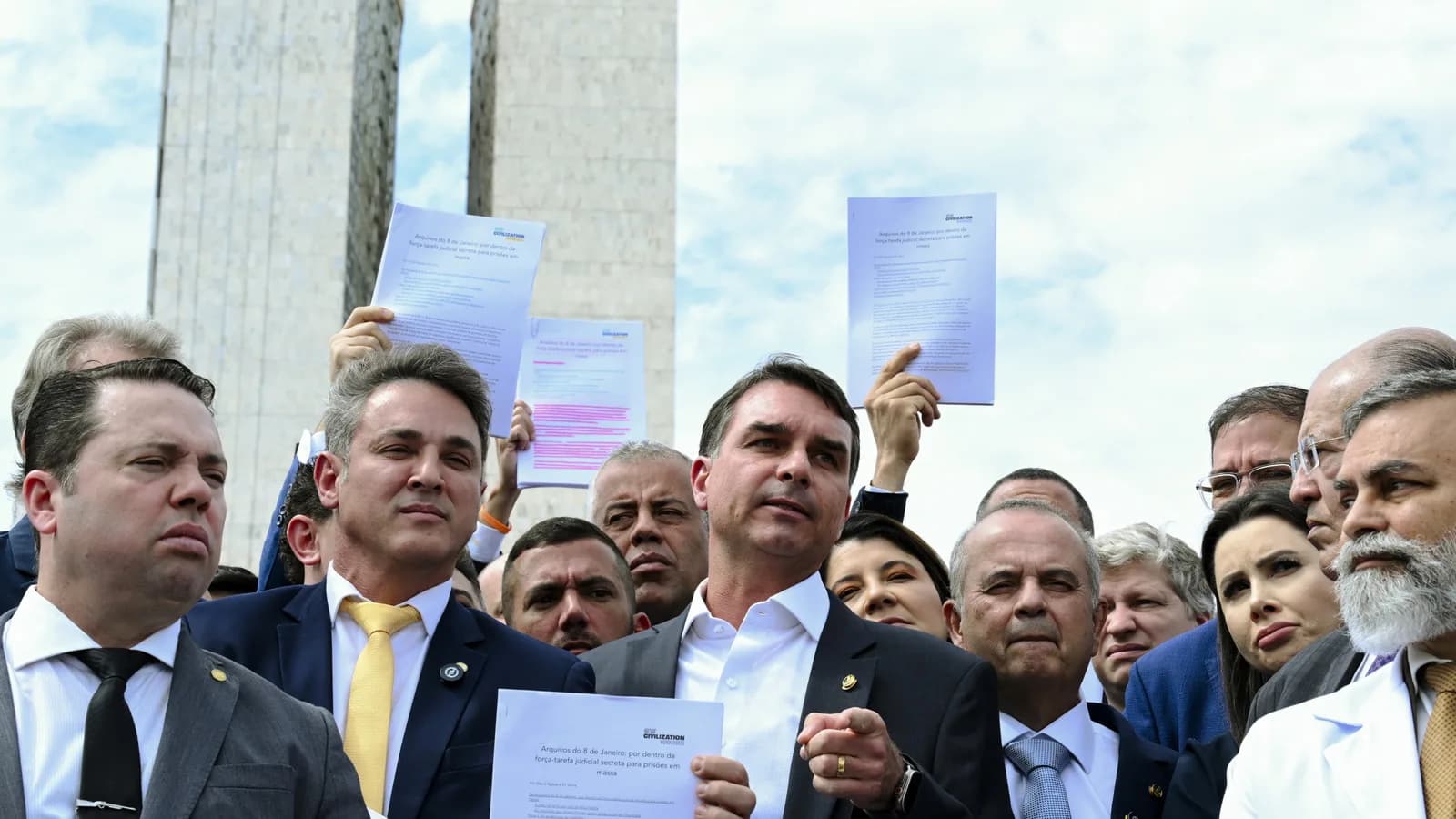 Flávio Bolsonaro ao lado de parlamentares da oposição segura documentos durante coletiva de imprensa