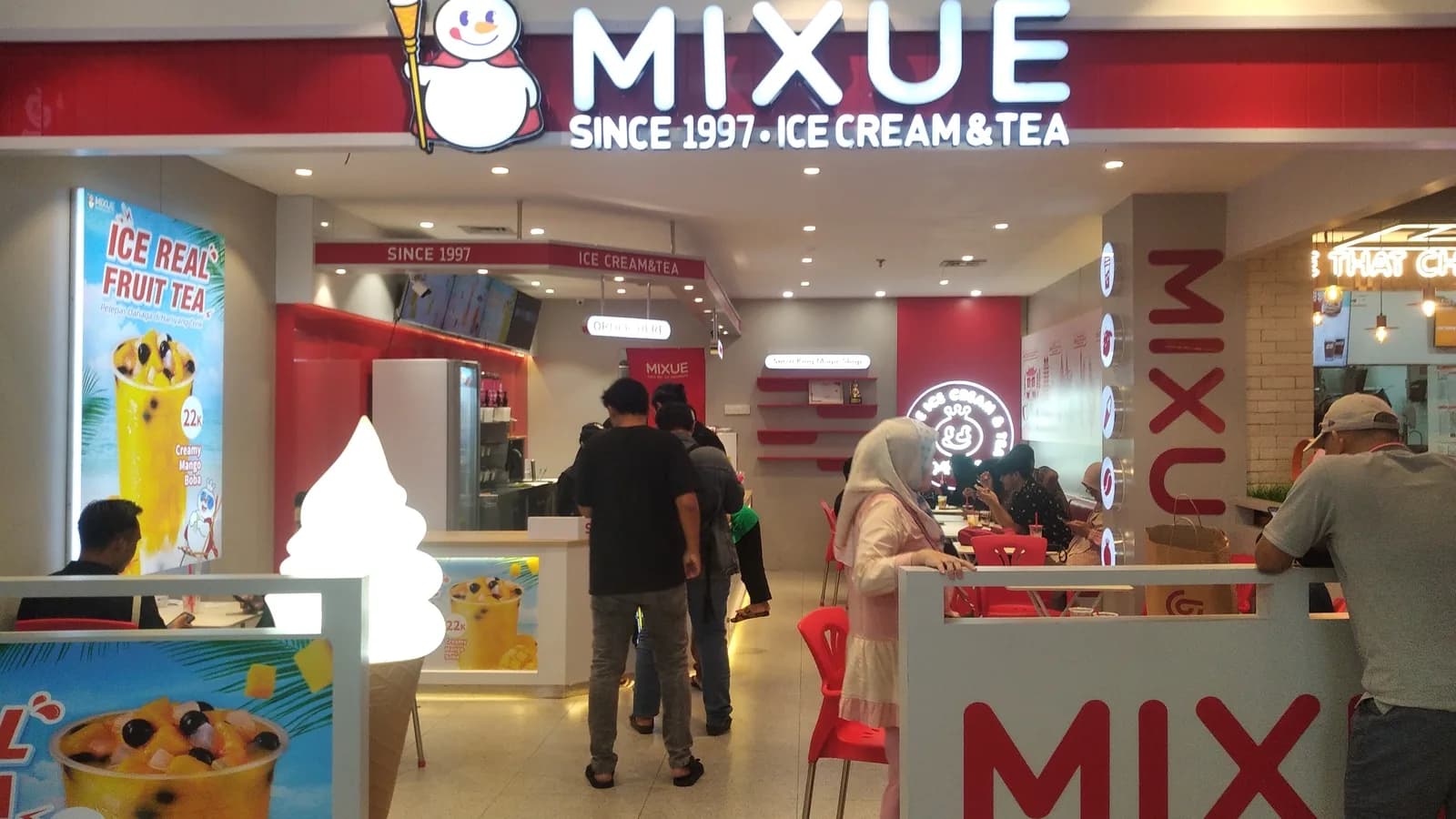 Fachada e interior de uma loja da Mixue com clientes (foto de arquivo, unidade no exterior)