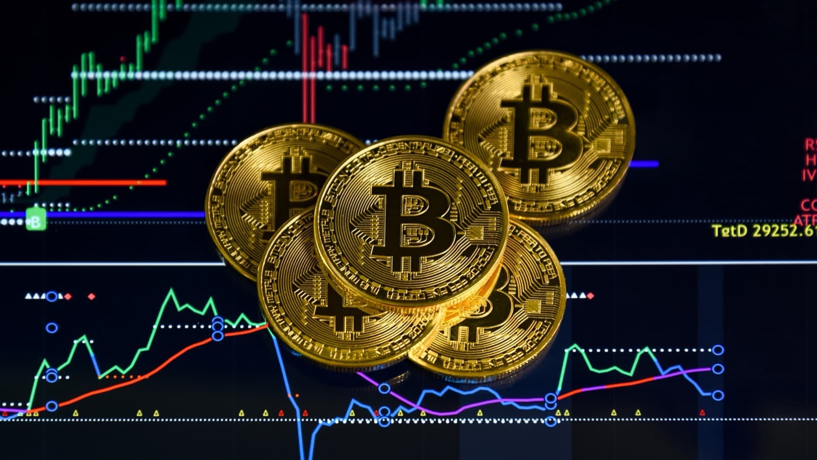 Moedas físicas de bitcoin sobre tela com gráfico de candles de mercado financeiro