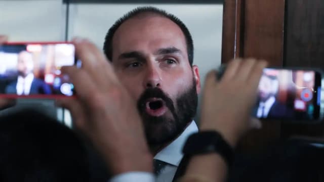 Eduardo Bolsonaro fala a repórteres cercado por celulares e câmeras
